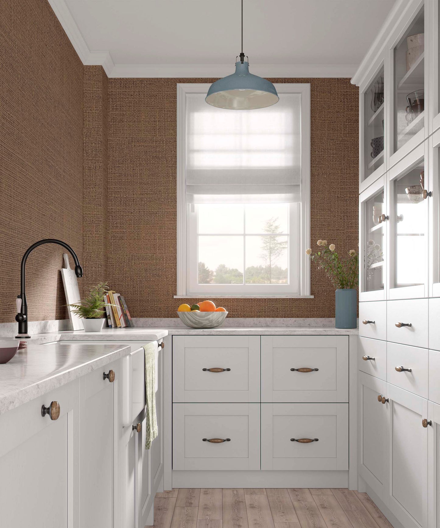 Bright kitchen with white cabinetry, a marble countertop, and a blue pendant light. A window with shades provides natural light, and a bowl of oranges sits on the counter. Textured brown walls and a potted plant add warmth.