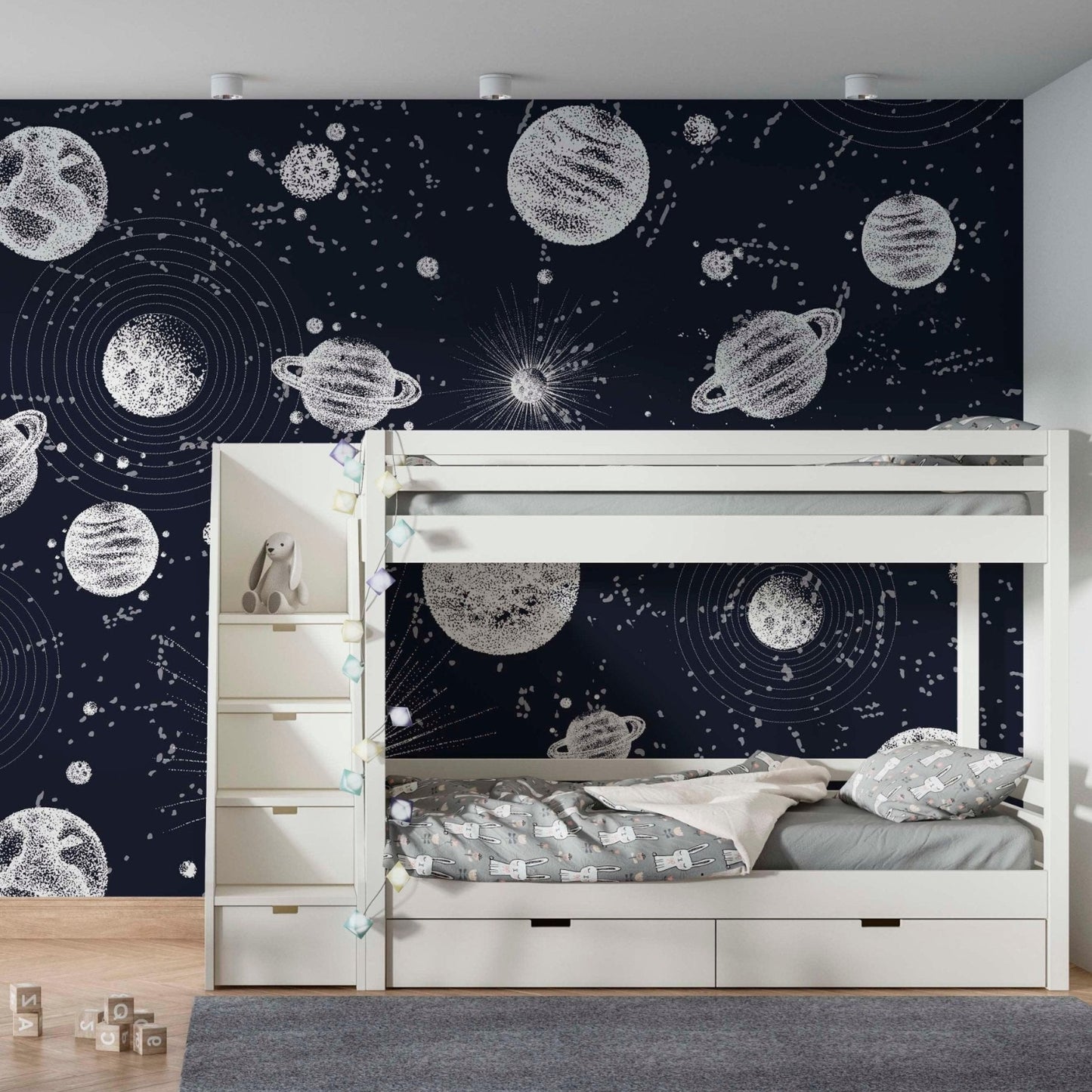 A kids bedroom featuring a white bunk bed and a space wallpaper mural with a dark blue background and white planets