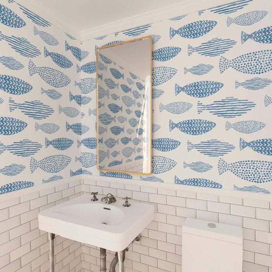 A classic powder room in white, showcasing a retro vanity, subway tile wainscoting, and wallpaper adorned with blue fish.