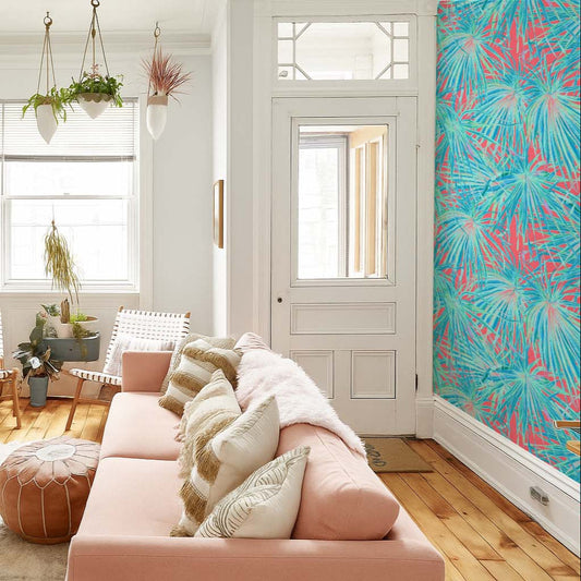 cat-659356549448 A bright, eclectic living room featuring a blush pink sofa, a bold teal and pink tropical palm leaf accent wall, and a large indoor cactus in a white woven basket.