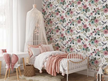 Girls nursery bedroom with vintage floral wallpaper featuring pink and blue flowers and birds behind a white bed with soft pink bedding and canopy