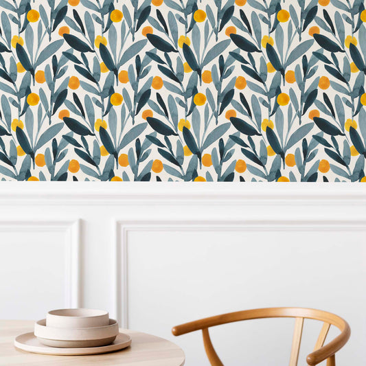 cat-659356549448   Modern dining room wall decorated with indigo blue leaf and yellow citrus watercolor wallpaper, featuring white wood wainscoting, a wooden chair, and minimalist tableware.