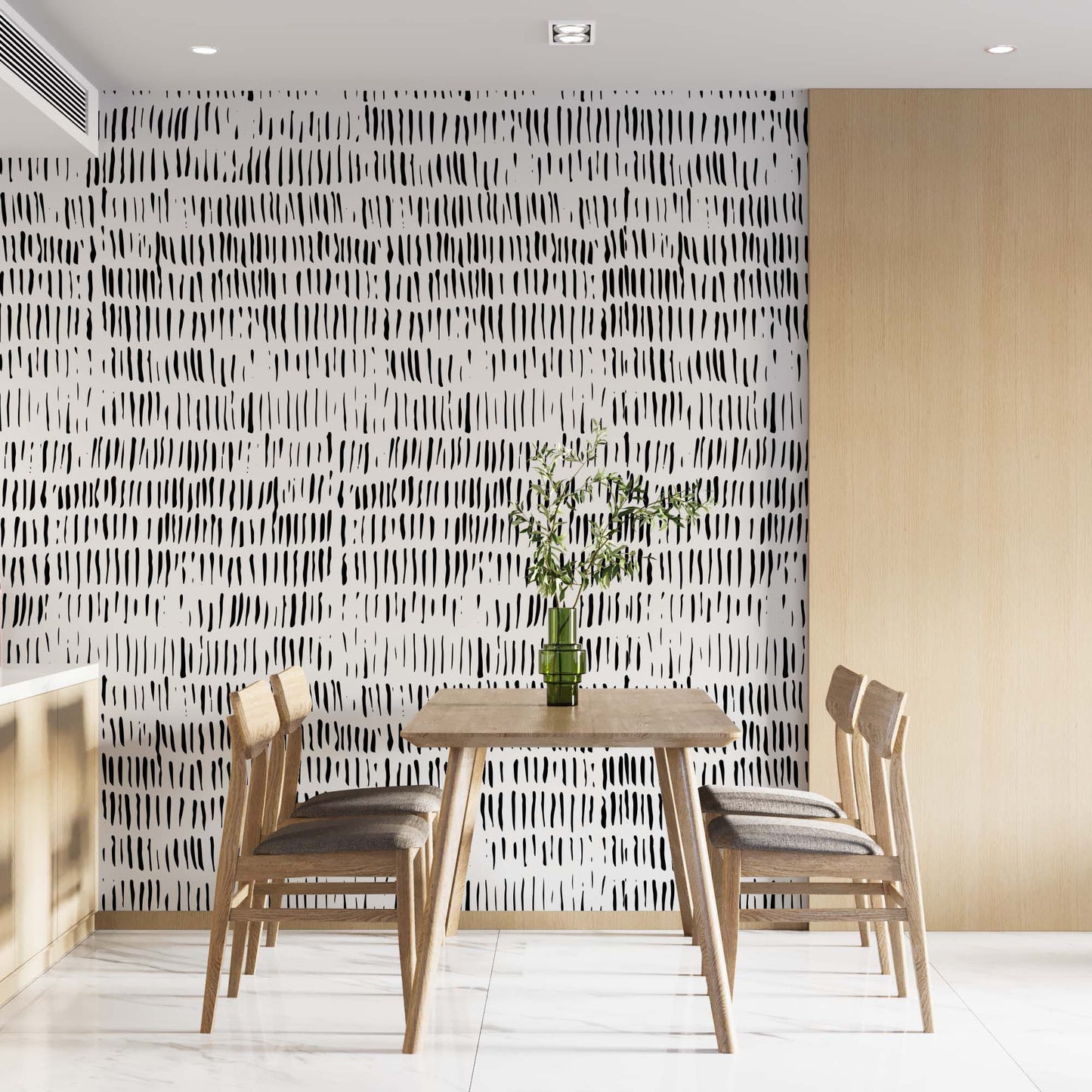 with irregular vertical strokes, adding a dynamic and artistic touch to the room. The wallpaper contrasts with the light wooden furniture and cabinetry, creating a minimalist and stylish atmosphere. A simple dining table is set with four wooden chairs, while a vase with green branches adds a natural accent to the sleek design.