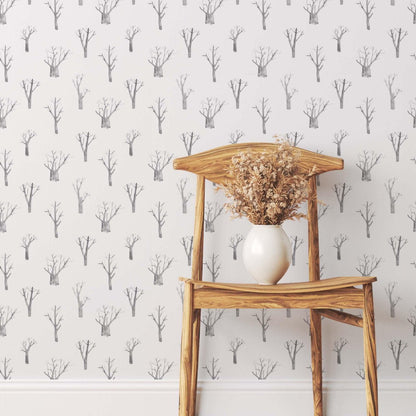 Wooden chair with dried branches against winter trees wallpaper in soft grey tones.