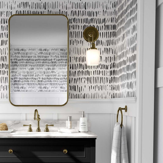 white wallpaper featuring a contemporary pattern of vertical, hand-drawn black ink strokes of varying lengths. It is styled in a modern bathroom above white wooden wainscoting.
