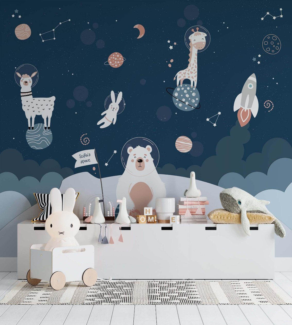 This playroom is features a space wallpaper mural with a llama, a giraffe and a bear on a planet. In dark blue and grey colors.