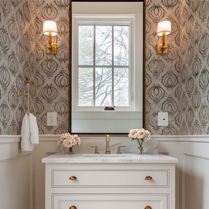 cat-610804236616 Elegant bathroom interior featuring tribal ethnic wallpaper in earth tones above white wainscoting, styled with a white marble vanity, brass fixtures, and a large arched mirror.