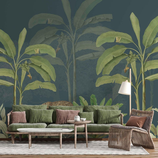 Living room interior with a green sofa and rattan furniture placed in front of a tropical jungle wall mural featuring large banana leaves, lush plants, and a leopard walking through the foliage on a dark teal background.
