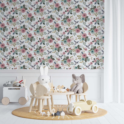 Nursery room with vintage floral wallpaper featuring pink and blue flowers and small birds on the wall above wooden children's furniture and toys.