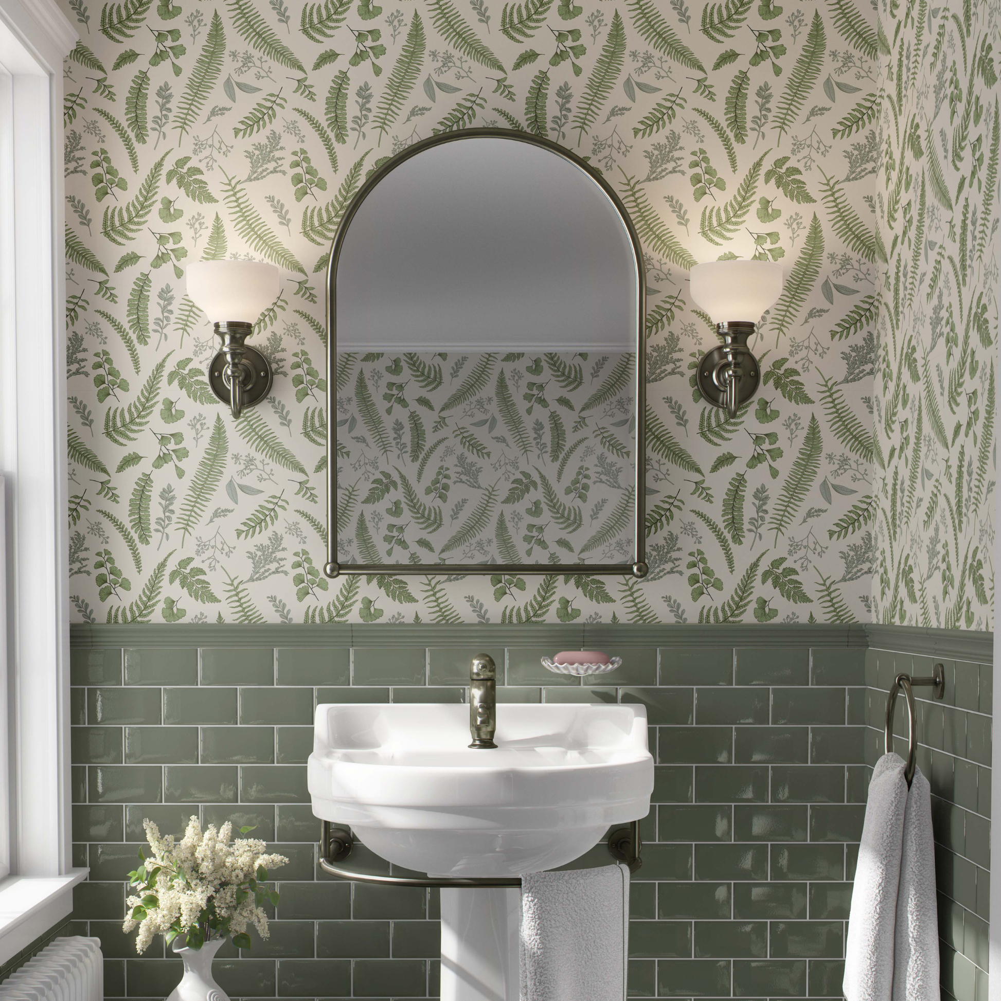 cat-610804236616 A luminous and classic bathroom featuring a lush botanical wallpaper with vibrant green fern fronds and delicate leaves on a white background. The pattern extends across the upper walls and ceiling, beautifully paired with deep emerald green subway tiles on the lower half. A white pedestal sink with brass fixtures is centered below an arched gold-framed mirror, flanked by elegant traditional wall sconces, creating a refreshing nature-inspired sanctuary.