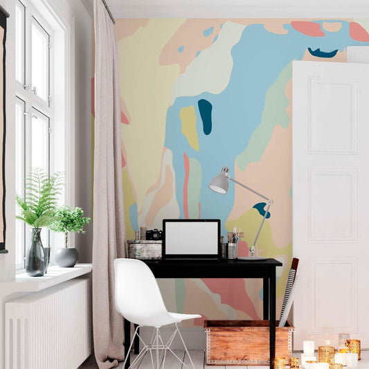cat-660961526088 Creative home office workspace featuring a large abstract pastel wall mural behind a black desk with a white chair and floor candles.
