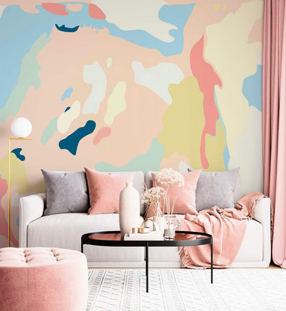Modern living room interior featuring an abstract pastel wall mural behind a white sofa with pink and grey cushions.