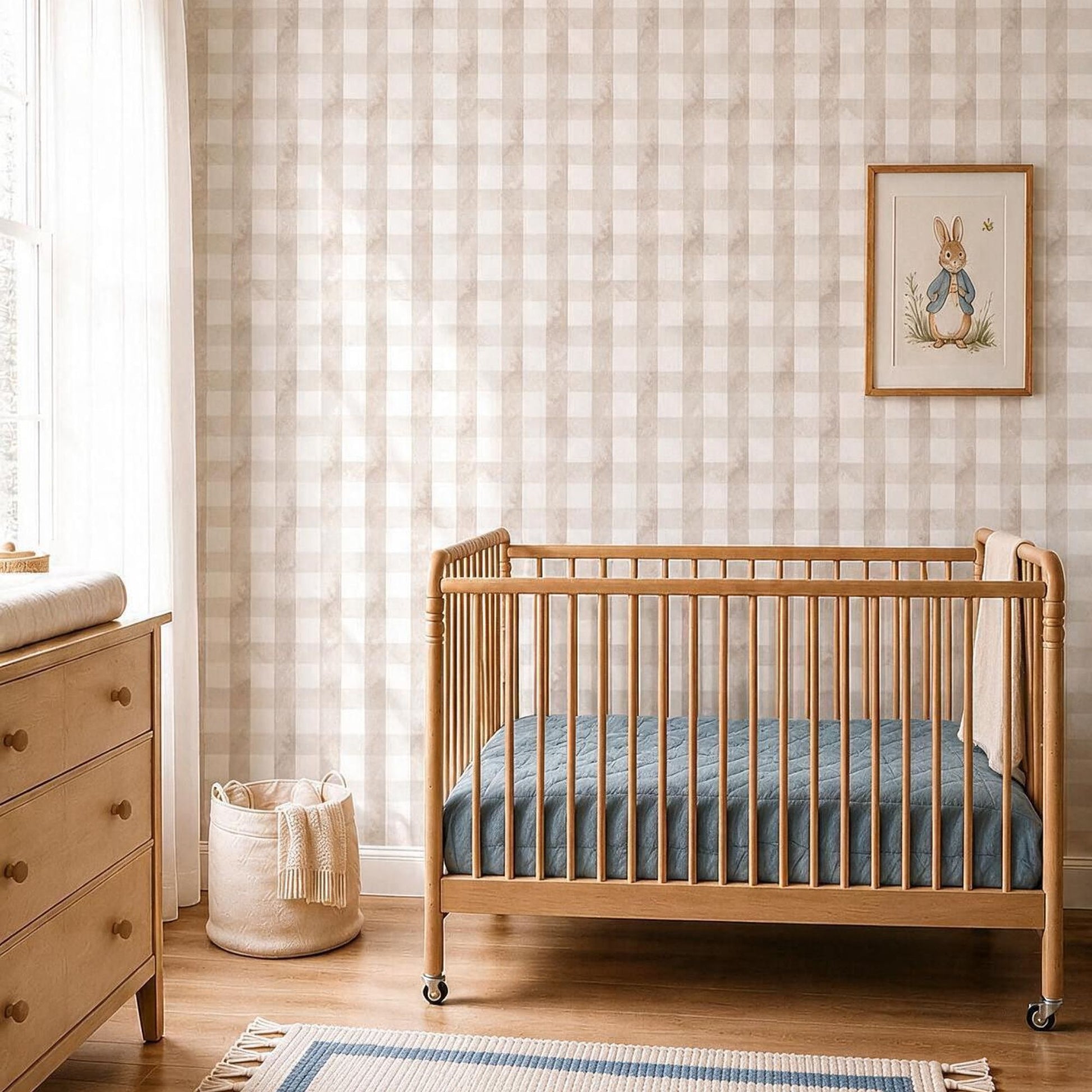 Neutral nursery with beige gingham wallpaper, light wood crib, soft blue bedding and Scandinavian-inspired decor.