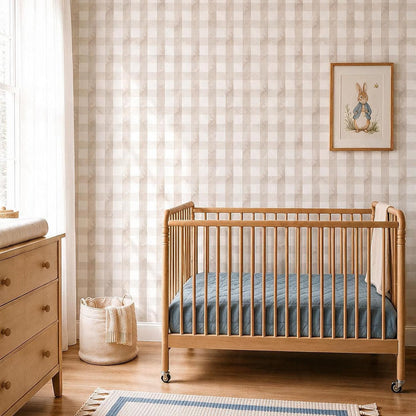 Neutral nursery with beige gingham wallpaper, light wood crib, soft blue bedding and Scandinavian-inspired decor.