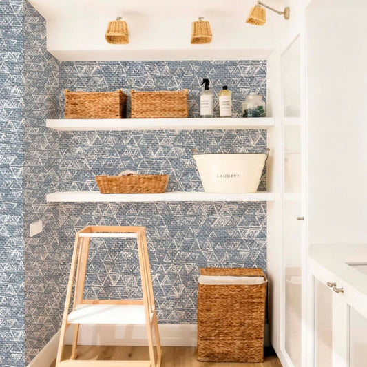 cat-615198490952 Modern laundry room interior featuring blue geometric triangles wallpaper, white floating shelves with wicker baskets, and natural wood accent
