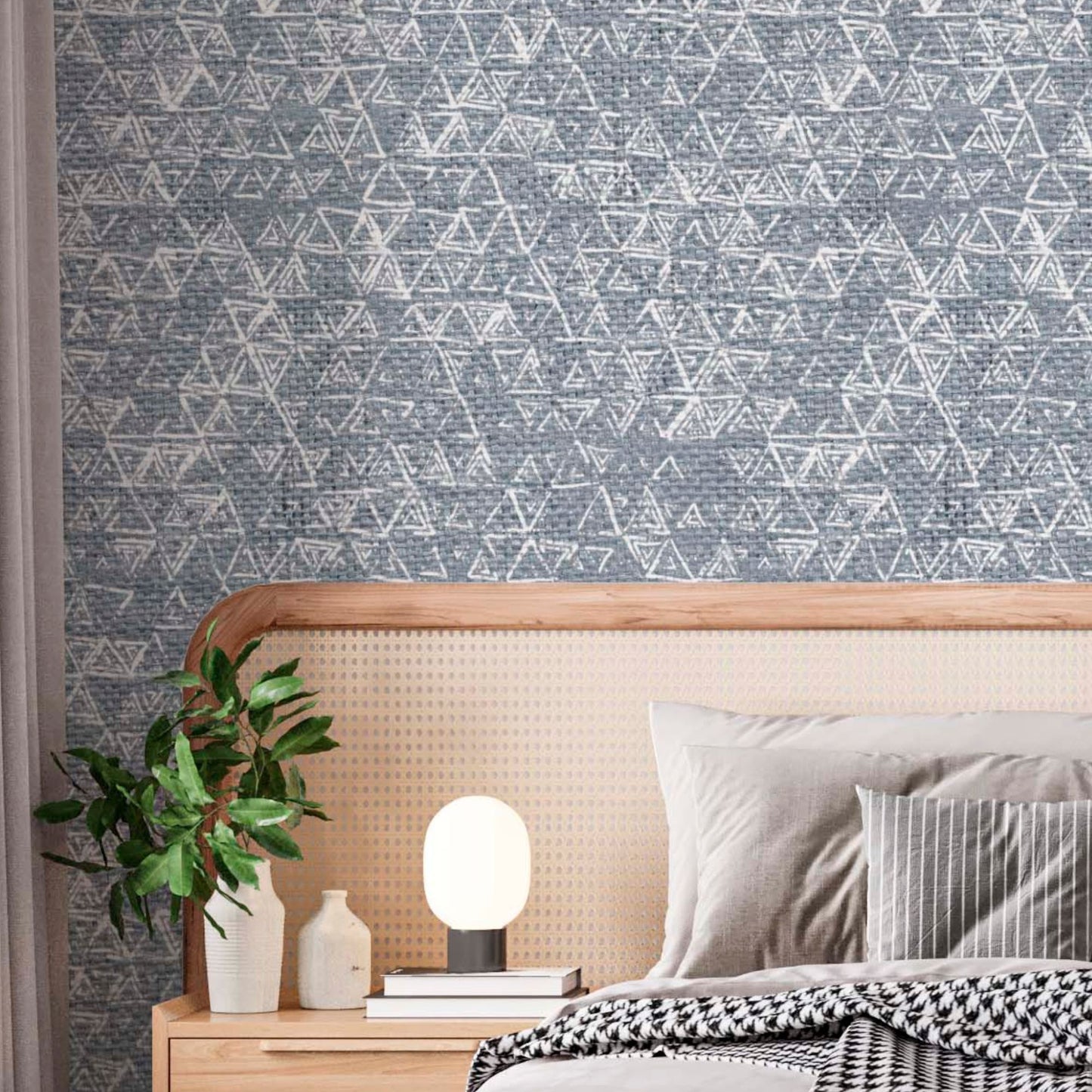 cat-616983200072 Modern bedroom featuring blue textured triangles wallpaper with a hand-drawn effect, styled with a rattan headboard, a wooden nightstand, and a minimalist globe lamp.