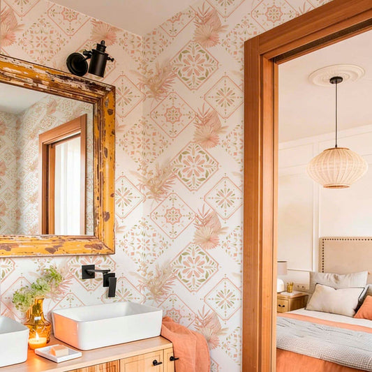Boho chic bathroom featuring geometric floral wallpaper in pink and green, a rustic wooden mirror, and a white vessel sink on a wooden vanity, with a view into a warm bedroom.