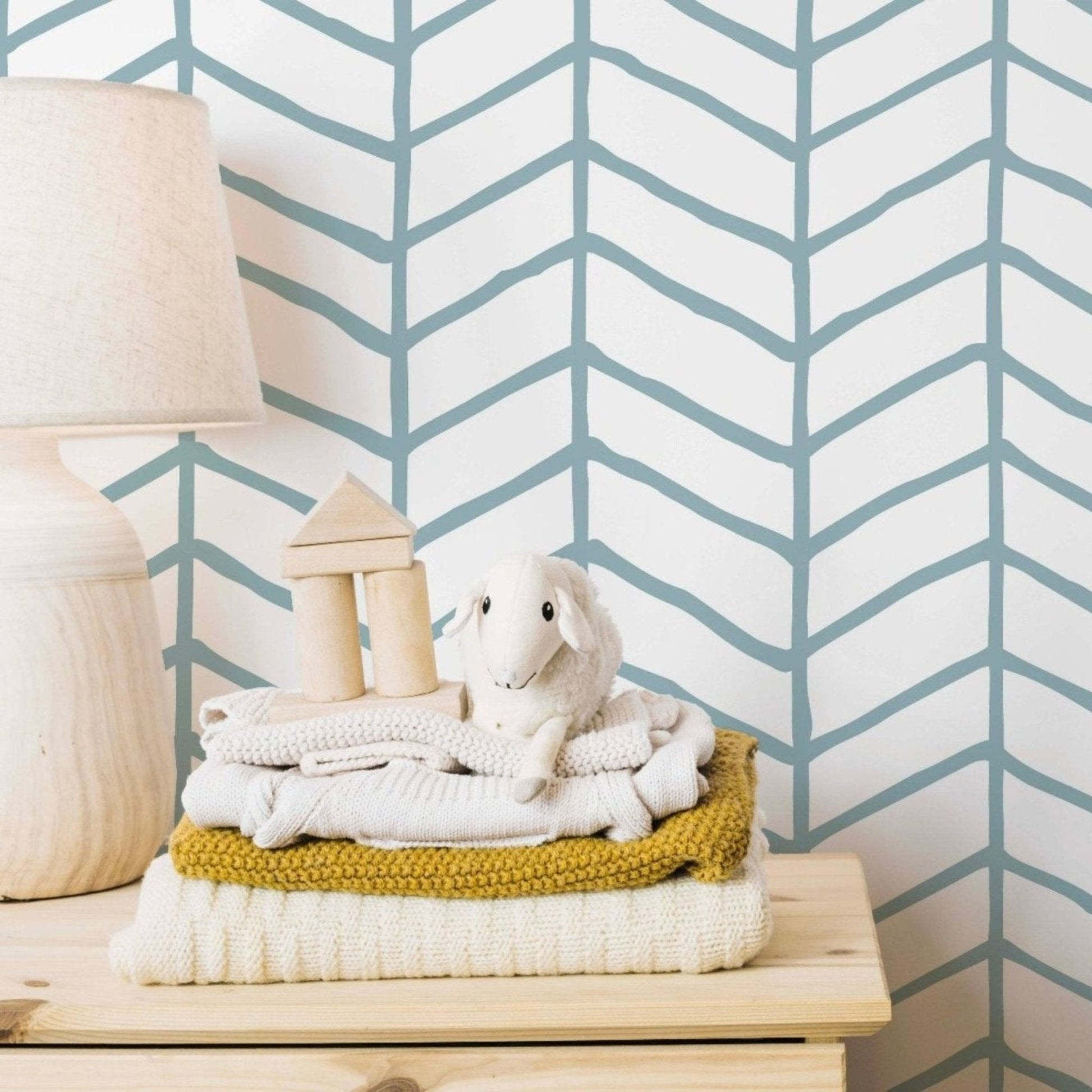 A bed adorned with soft linens, complemented by a striking white and blue chevron wallpaper in the background.