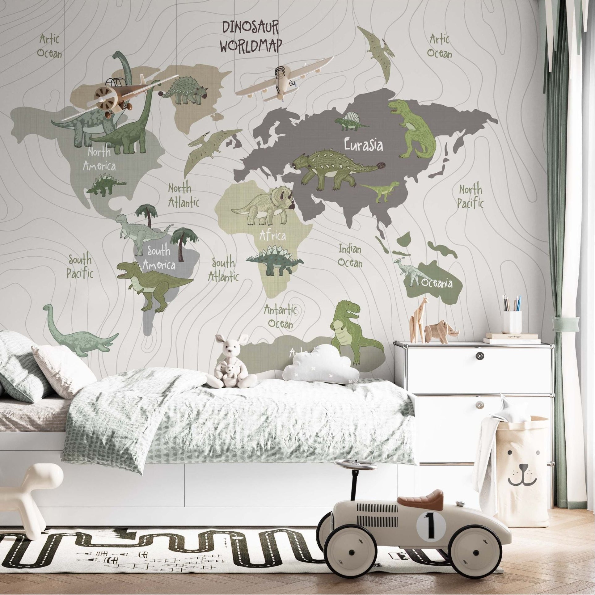 A bright children's bedroom featuring a large dinosaur world map mural, a white bed with patterned bedding, and a vintage-style toy racing car on a road-themed rug.