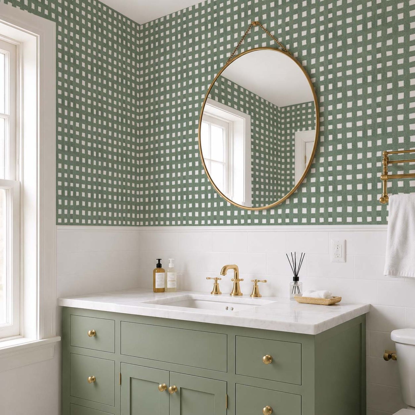 cat-610804236616 Small bathroom with muted green checkered wallpaper, sage green vanity, brass fixtures and white subway tile.