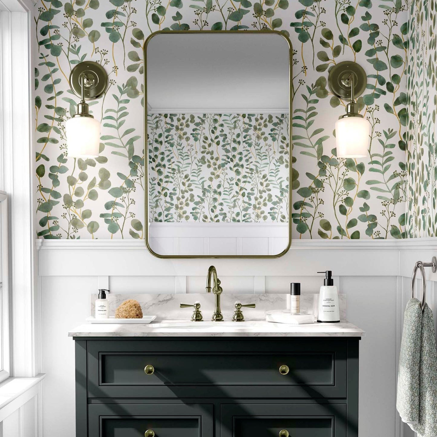cat-610804236616 Modern bathroom with green eucalyptus watercolor wallpaper, a black vanity, and a brass-framed mirror.