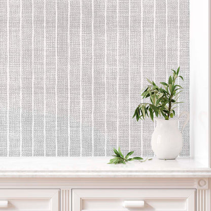 cat- 659356549448 Close-up of a grey and white textured stripe wallpaper above a white marble countertop with a white ceramic pitcher holding olive branches.