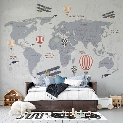 cat-610568044872 Grey world map wallpaper mural with hot air balloons and vintage planes in a kids bedroom with dark wood bed and wooden toys