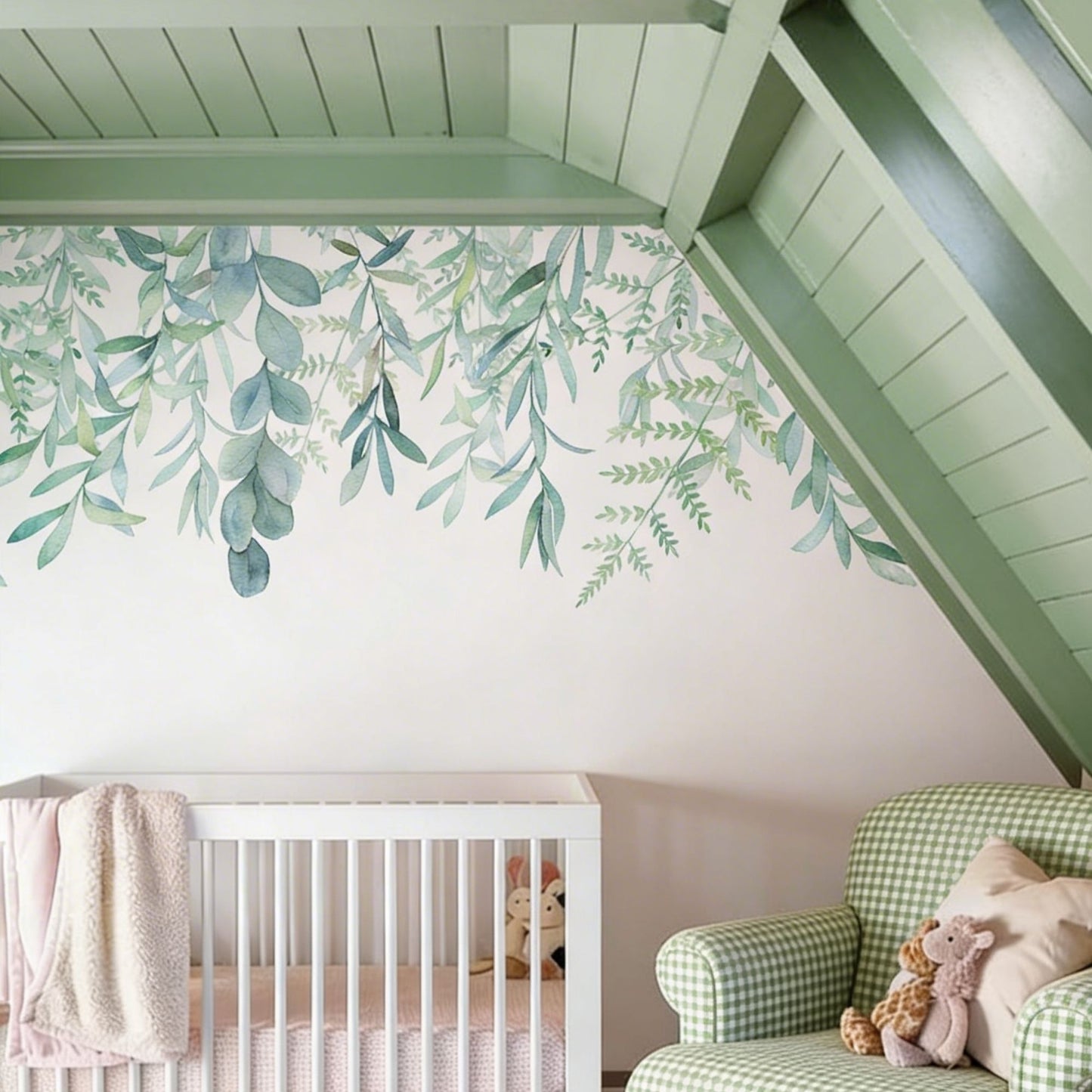 cat-610568044872 Hanging leaves wallpaper mural with soft green botanical leaves in a nursery with white cot, green checked armchair and sloped painted ceiling
