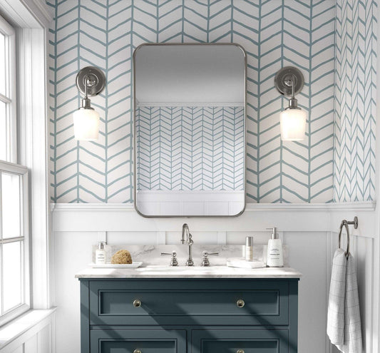 cat-610804236616 Modern bathroom featuring a teal and white hand-drawn herringbone wallpaper on the upper wall, styled with a navy blue vanity, marble countertop, and a rectangular mirror.