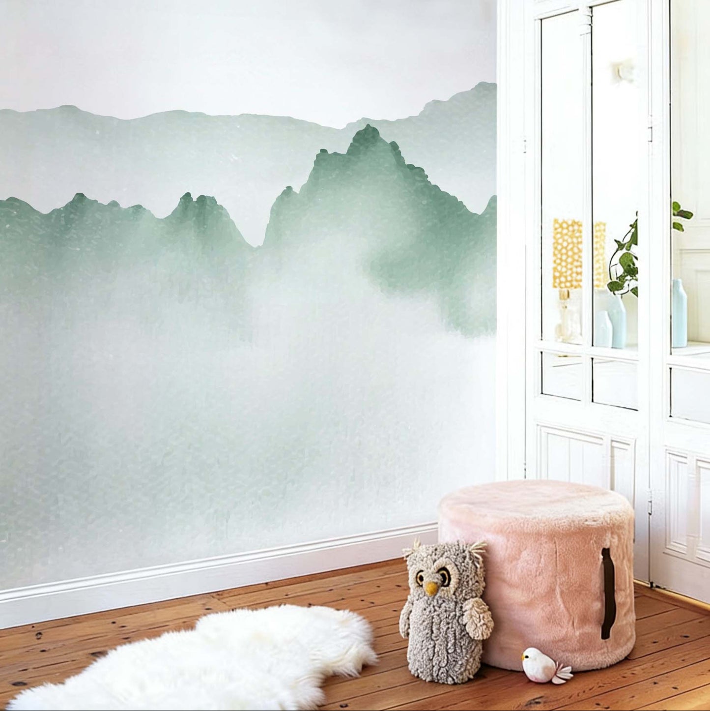 cat-610568044872 Decorative kids wallpaper featuring soft green watercolor mist and mountain ridges in a playroom corner with a pink plush pouf, an owl soft toy, and a white fluffy rug.