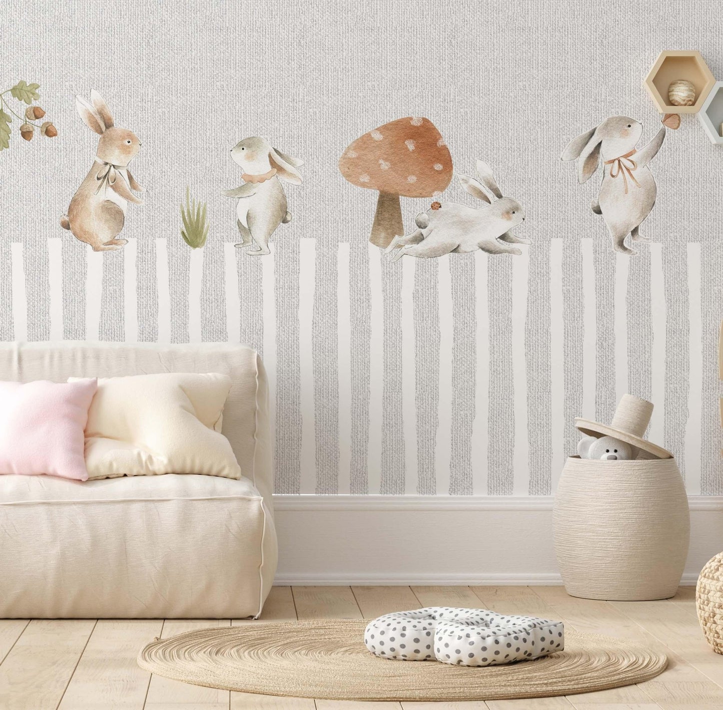Decorative kids wallpaper featuring a storybook forest with watercolor bunnies on a playroom wall behind a beige modular floor sofa and a round jute rug.