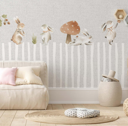 Decorative kids wallpaper featuring a storybook forest with watercolor bunnies on a playroom wall behind a beige modular floor sofa and a round jute rug.
