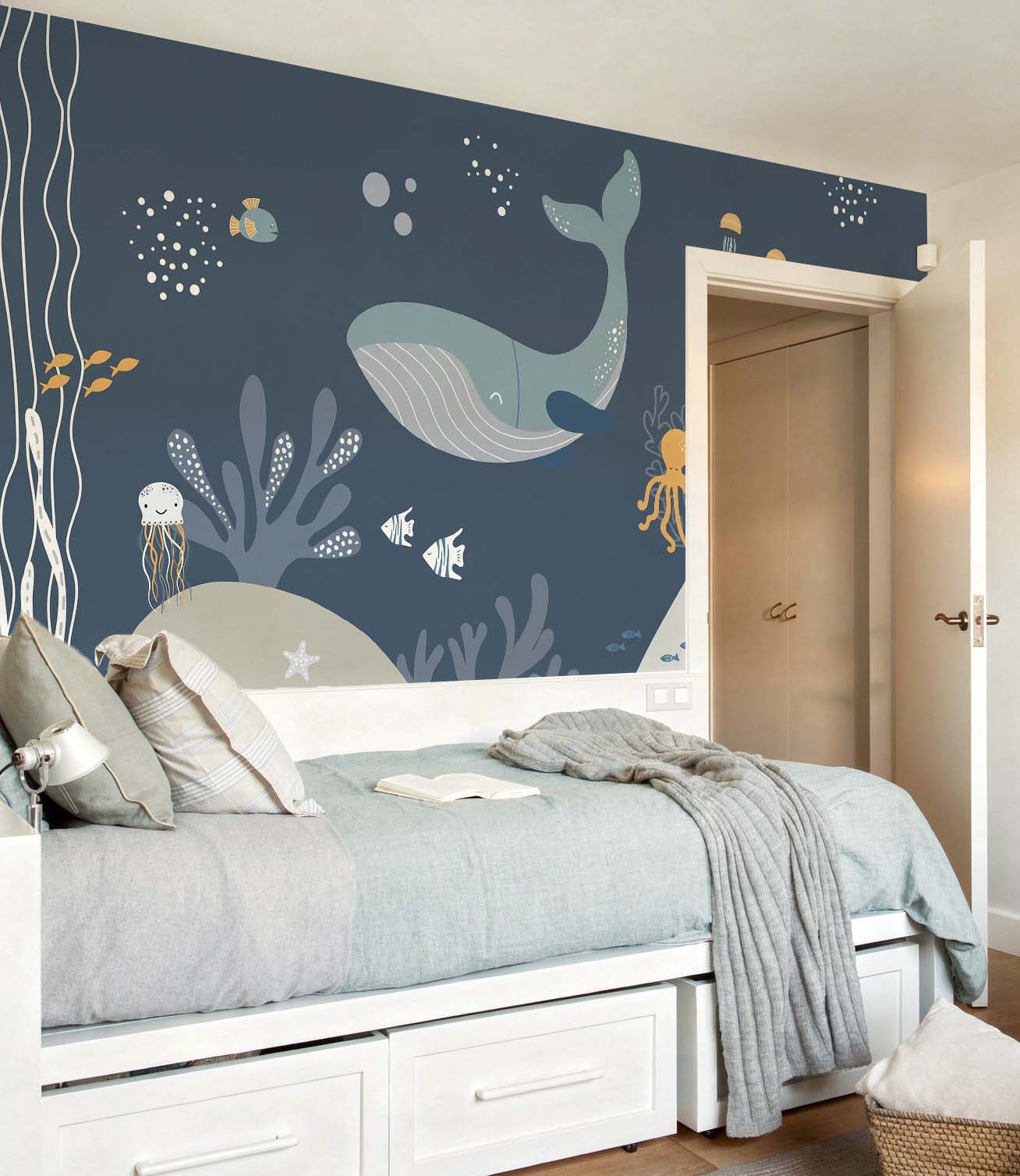 cat-661212758344  Decorative kids wallpaper featuring an illustrated dark blue underwater scene with whales behind a white trundle bed with light blue and grey bedding.