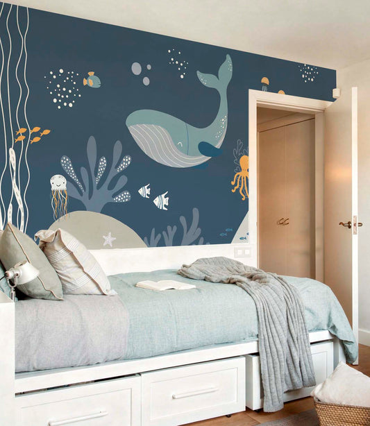 cat-661212758344  Decorative kids wallpaper featuring an illustrated dark blue underwater scene with whales behind a white trundle bed with light blue and grey bedding.
