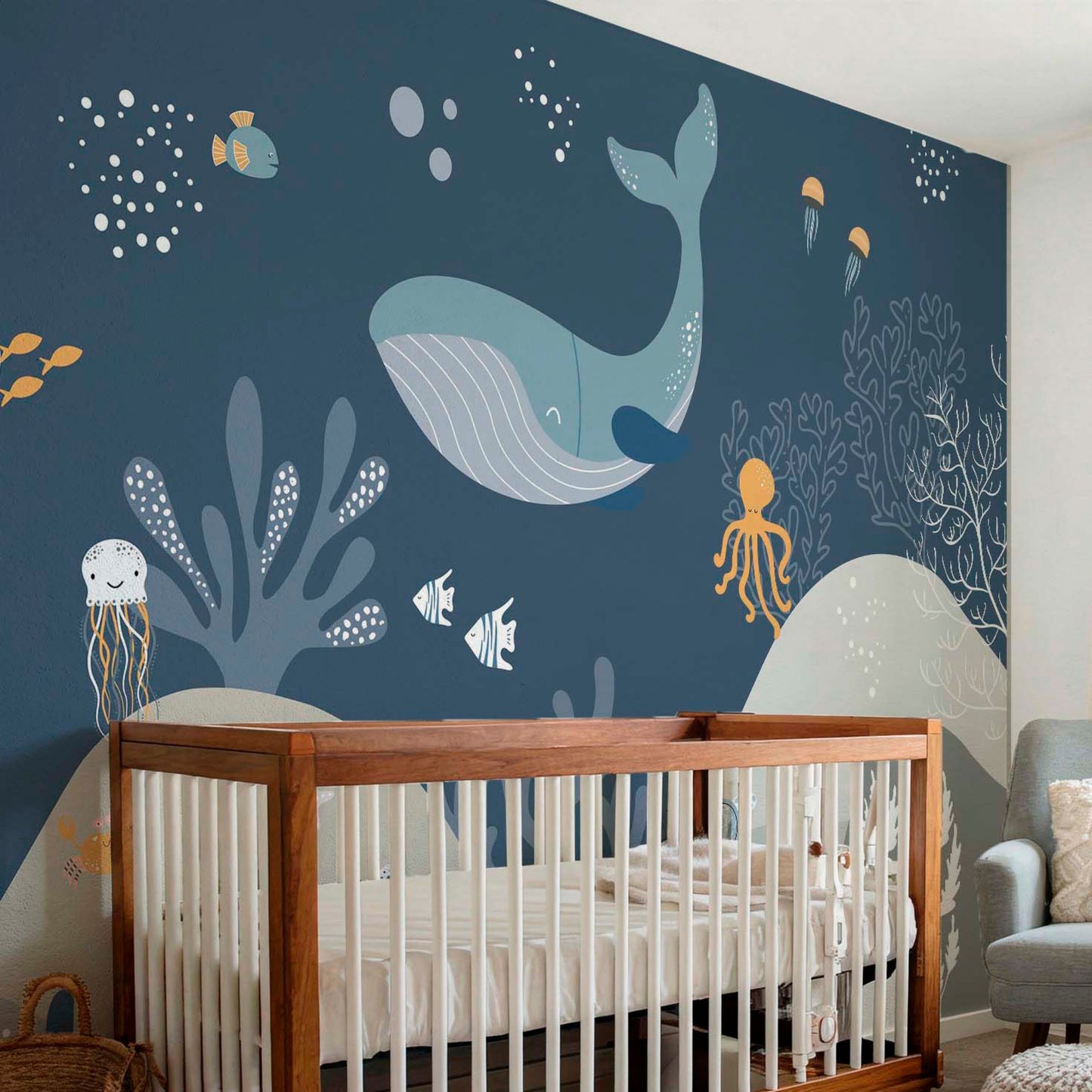 Decorative kids wallpaper featuring an illustrated dark blue underwater scene with a large whale behind a natural wood crib in a modern baby nursery.