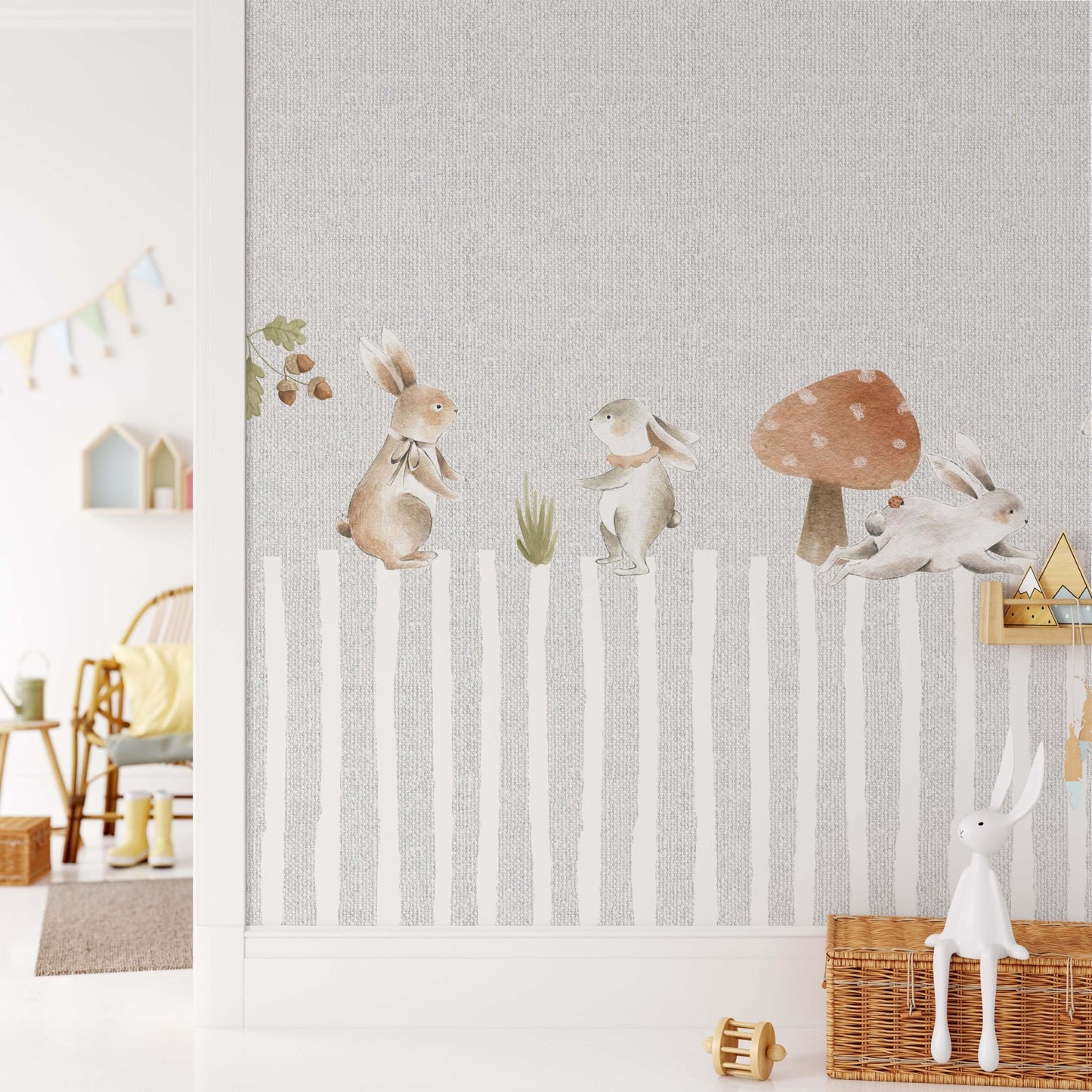 Decorative kids wallpaper featuring watercolor bunnies over a grey faux linen textured striped background on a nursery wall next to wicker baskets and wooden accessories.
