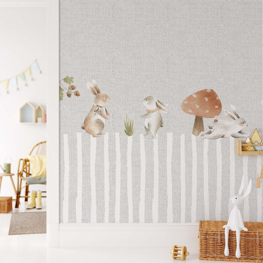 Decorative kids wallpaper featuring watercolor bunnies over a grey faux linen textured striped background on a nursery wall next to wicker baskets and wooden accessories.