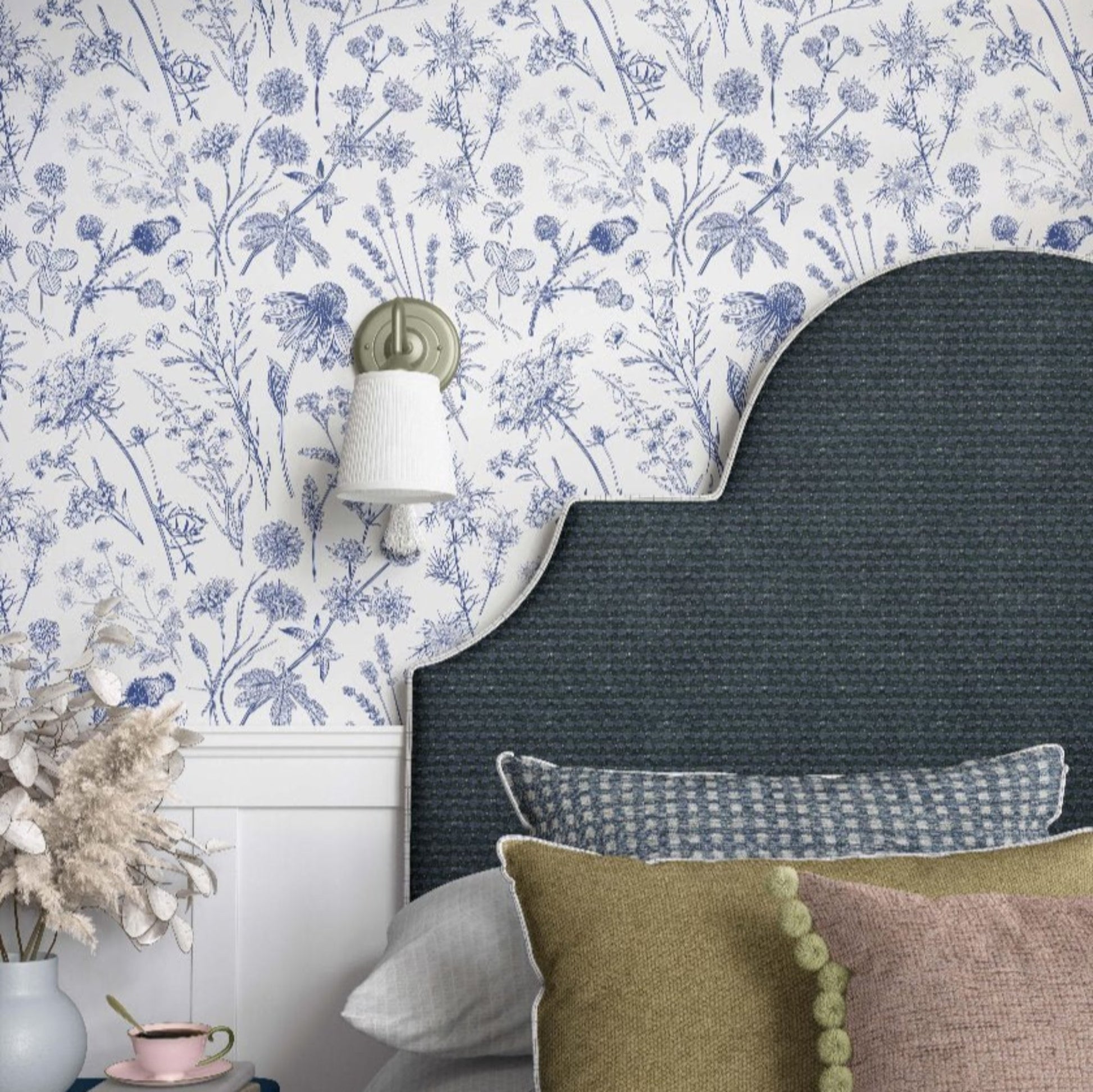 A beautifully designed blue and white floral wallpaper decorates the bedroom wall, adding charm and sophistication.