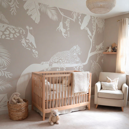 Neutral jungle animal wallpaper mural in a cozy nursery with crib and armchair