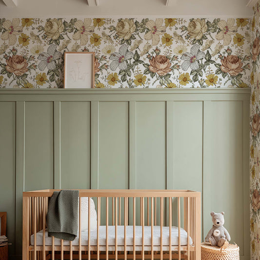Baby nursery featuring vintage floral wallpaper in ochre and dusty pink tones, sage green wainscoting, a natural wood crib, and warm rustic decor.