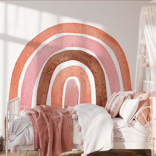 A children's bedroom with a white bed, pink and white bedding, a rainbow peel and stick wallpaper mural, canopy with string lights, and soft toys on a light wooden floor—perfect for playful children decor.