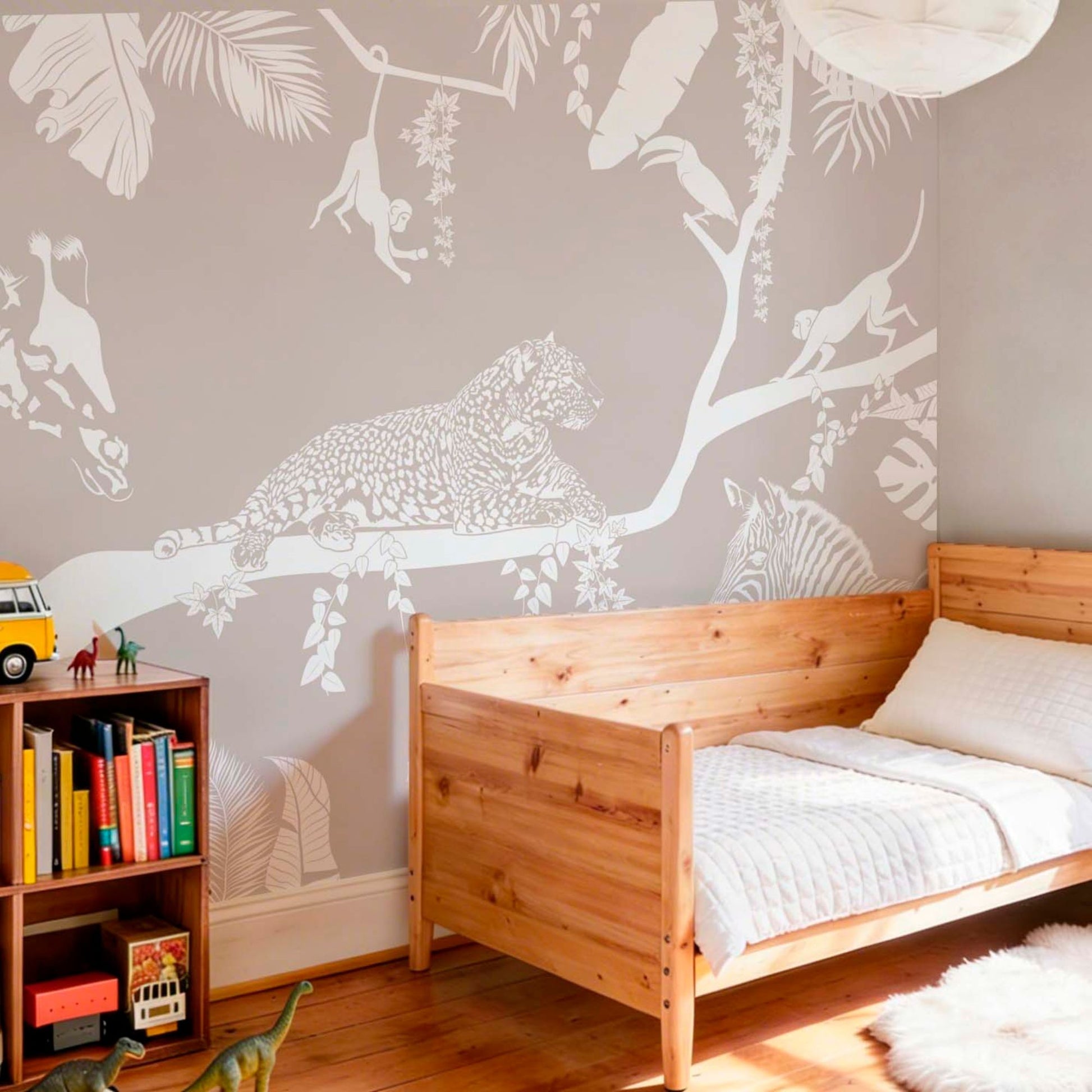 Safari animal wallpaper mural with jungle scene in a kids bedroom featuring wooden bed and bookshelf