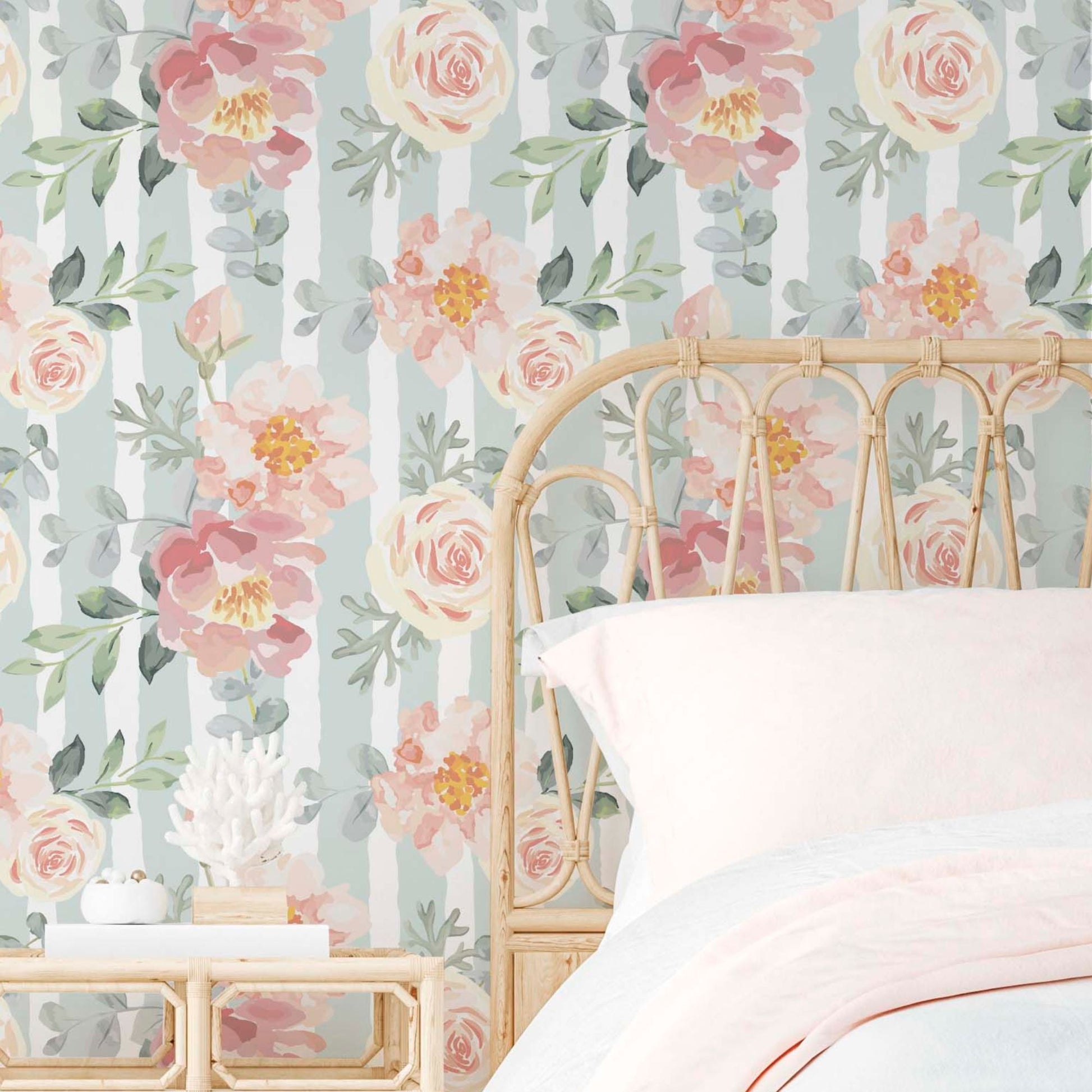 cat-616983200072 A bright and airy bedroom featuring a wall covered in sage green and white vertical striped wallpaper adorned with large, hand-painted watercolor pink peonies and cream roses. A light natural rattan headboard sits against the wall, topped with crisp white and soft pink bedding for a romantic, vintage-inspired look.