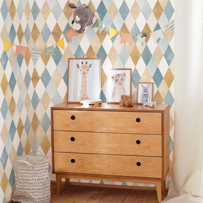 Nursery wall featuring harlequin watercolor wallpaper in ochre and blue tones, styled with a mid-century wooden dresser and animal illustrations.
