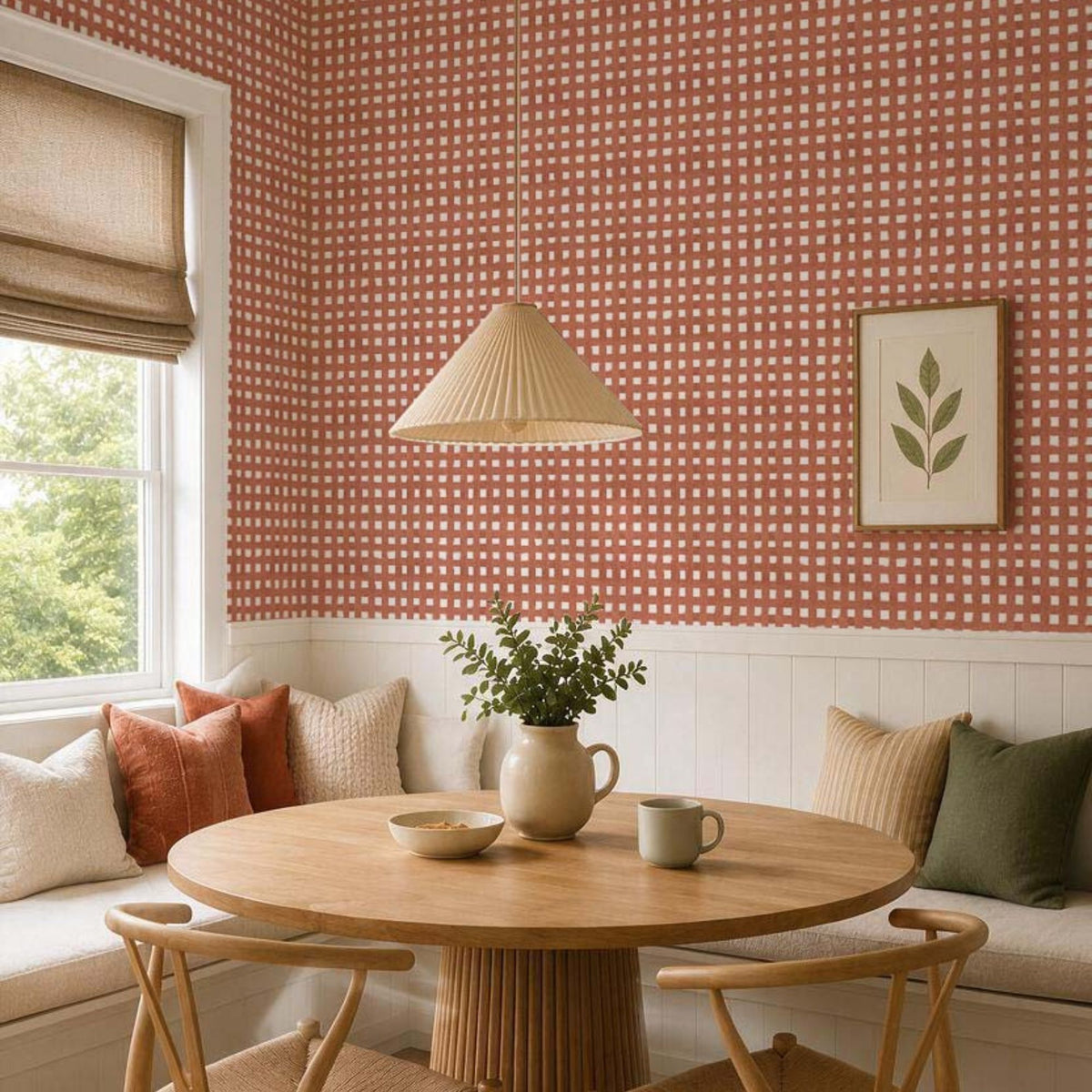 Cozy breakfast nook with terracotta checkered wallpaper, white wainscoting, a round oak table and woven dining chairs.