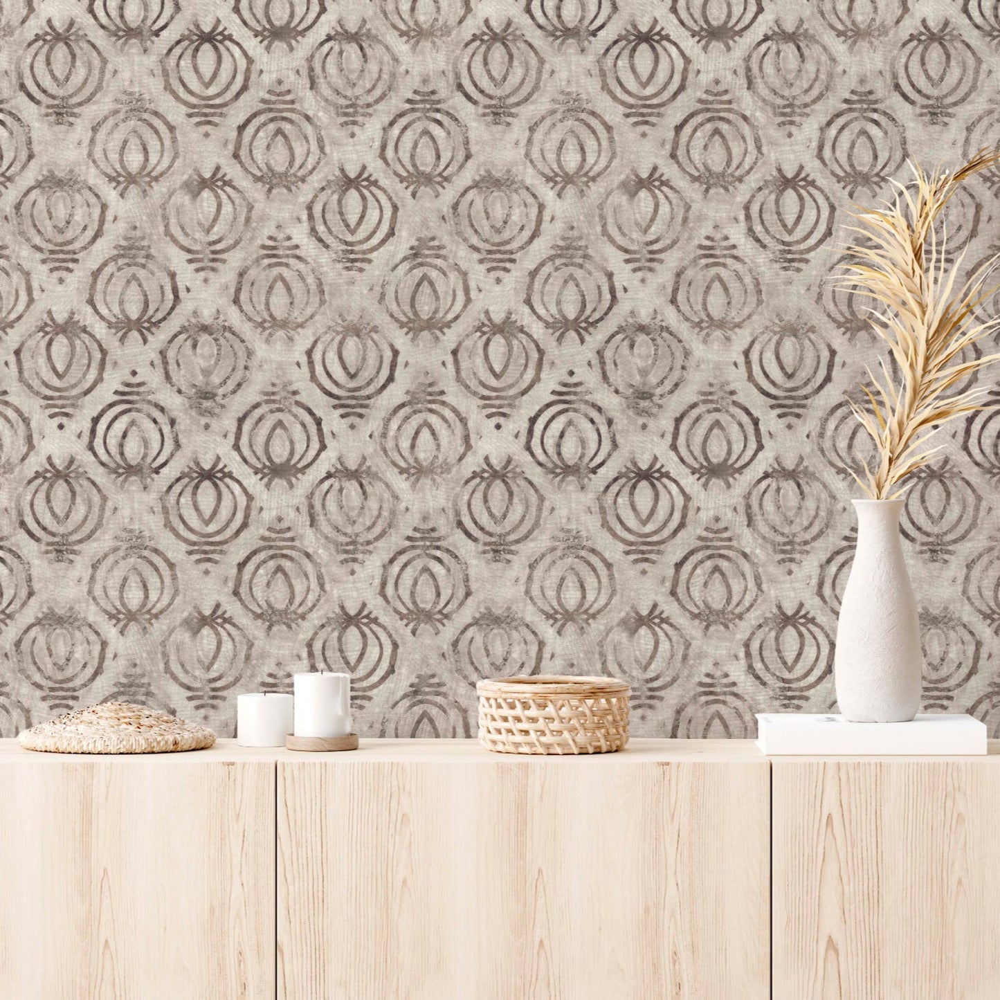Modern interior featuring tribal block print wallpaper in earth tones, styled with a light wood credenza, white ceramic vases with dried botanicals, and minimalist candles.