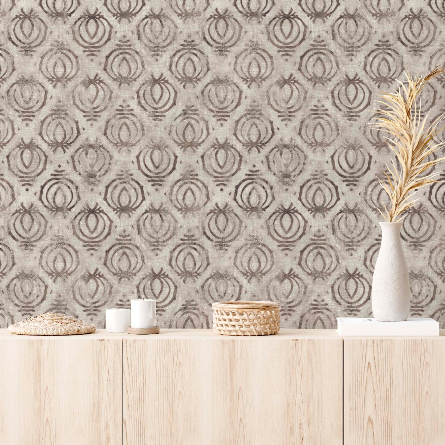 Modern interior featuring tribal block print wallpaper in earth tones, styled with a light wood credenza, white ceramic vases with dried botanicals, and minimalist candles.