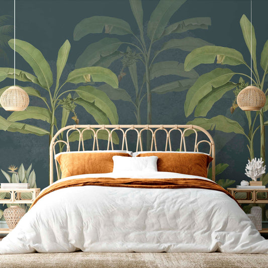 cat-610567389512 A cozy bohemian bedroom featuring a large tropical wall mural with dark teal background and green banana leaves, a curved natural rattan headboard, and burnt orange velvet pillows on white bedding