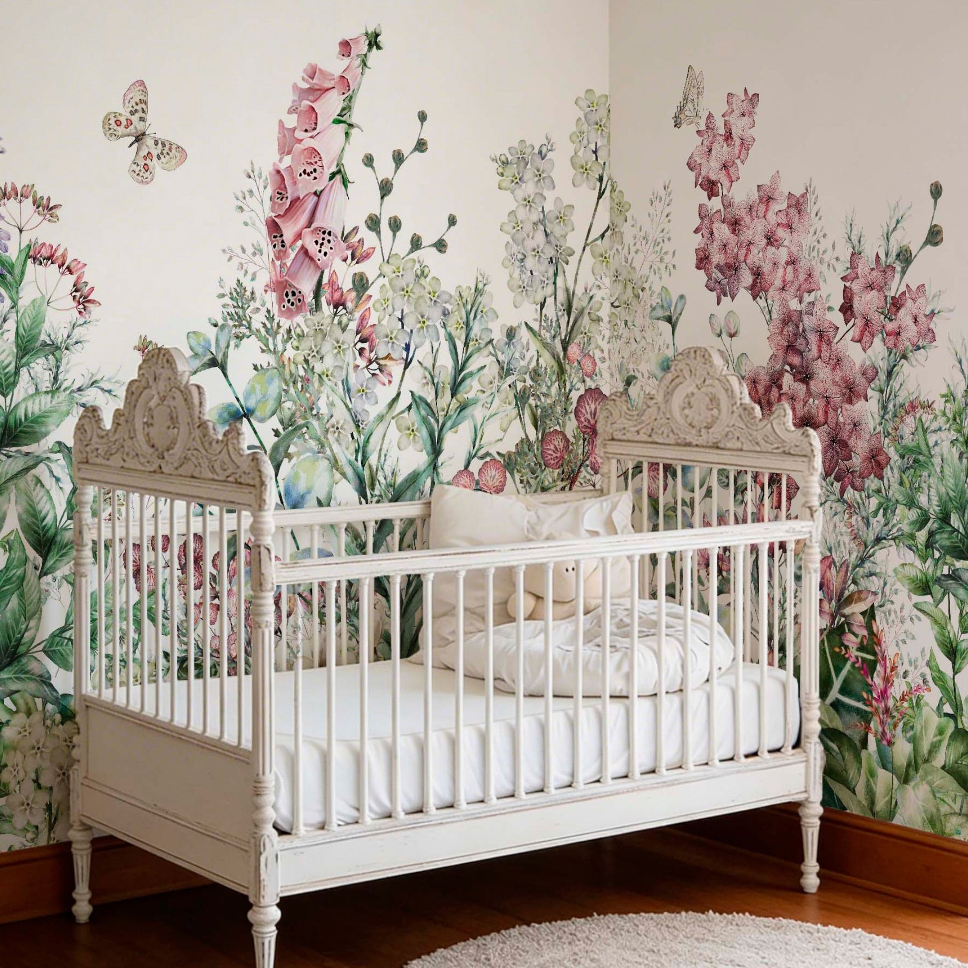 Vintage white wooden crib in a nursery featuring a large watercolor wall mural of pink foxgloves, wildflowers, and butterflies.
