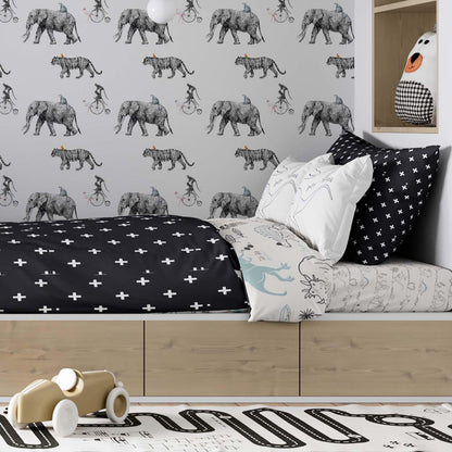 Black and white circus-themed wallpaper mural by Olively Home in a modern kids' room with a wooden platform bed and black cross-patterned bedding
